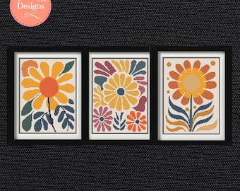 Puede incluir: Tres obras de arte florales enmarcadas. Cada una presenta un diseño floral estilizado diferente en tonos de amarillo, naranja, azul y verde. La obra de arte está sobre un fondo crema y enmarcada en negro. La esquina superior izquierda tiene un círculo rosa con el texto "TeaJeigh Designs".