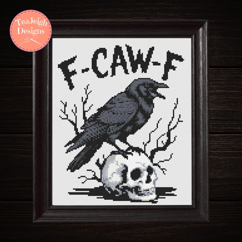 May include: Framed cross-stitch art featuring a black crow perched atop a skull, with the text "F-CAW-F" above. The artwork is set against a white background and framed in a dark brown wooden frame. The design includes bare branches.