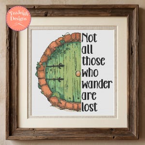 May include: A framed cross-stitch pattern featuring a semi-circular green wooden door with a brick archway and ivy, accompanied by the black text "Not all those who wander are lost" on a white background, encased in a rustic brown wooden frame.