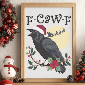 Könnte beinhalten: Gerahmtes Kreuzstich-Kunstwerk mit einem schwarzen Raben, der einen Weihnachtsmannhut trägt und auf einem Ast mit roten Beeren und grünen Blättern sitzt. Der Text "F-Caw-F" steht über dem Raben, mit einem gelben Mond und Santa's Schlitten im Hintergrund. Weihnachten.