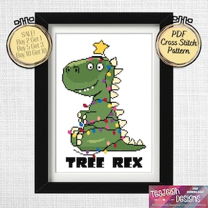 May include: A cross stitch pattern featuring a green dinosaur dressed as a Christmas tree with colourful lights. The text "TREE REX" is below the dinosaur.