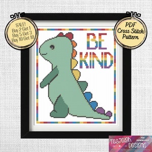 Pode incluir: Um padrão de ponto cruz com um dinossauro verde com uma cauda arco-íris e as palavras "Seja gentil" em letras arco-íris.