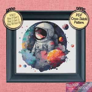 May include: A PDF cross stitch pattern featuring a watercolor-style illustration of an astronaut in a space suit standing in front of a planet with a colorful nebula background. The pattern includes the text "SALE! Buy 2 Get 1, Buy 5 Get 3, Buy 10 Get 10".