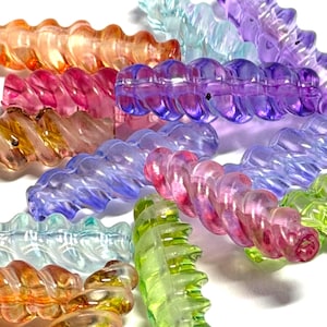 May include: A collection of colorful, transparent, spiral-shaped beads in shades of orange, pink, purple, blue, and green. The beads have a wavy texture and are scattered against a white background.