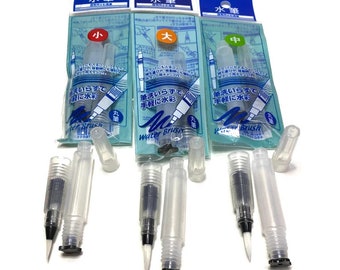 Op de afbeelding: Een verzameling transparante waterpenselen met zwarte punten en doppen, verpakt in blauw en wit plastic. De verpakking bevat Japanse tekst en de merknaam "Sakura". De pennen zijn ontworpen voor aquarel schilderen.
