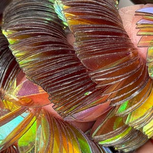 May include: A collection of iridescent, semi-circular, thin plastic scales arranged in overlapping rows. The scales feature a color-shifting finish that transitions between deep brown, amber, and vibrant lime green depending on the light reflection.