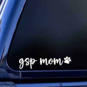 May include: White vinyl decal with the text "gsp mom" and a white paw print on a black car window.