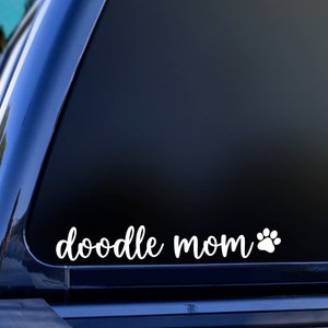 White Doodle Mom decal with a paw print placed on the window of a car.