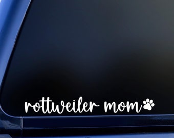 May include: A white vinyl decal with the text "rottweiler mom" and a paw print on a blue car window.