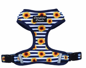 May include: A blue and white striped dog harness with a sunflower pattern and the text "Delightful Dapple" on the front.