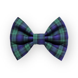 May include: A green and blue tartan bow tie. The bow tie is made from a soft, silky fabric and has a classic bow shape.