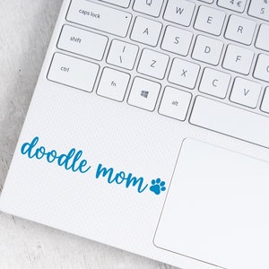 Blue Doodle Mom decal with a paw print placed on a laptop.