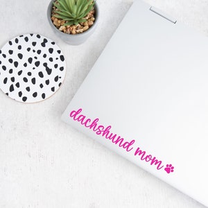 Pink Dachshund Mom decal with a paw print placed on a laptop.