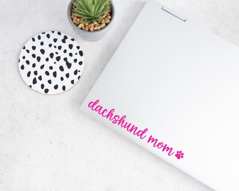 Pink Dachshund Mom decal with a paw print placed on a laptop.