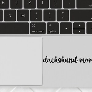 Black Dachshund Mom decal with a paw print placed on a laptop.