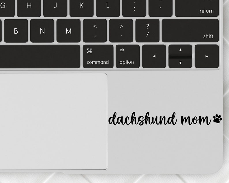 Black Dachshund Mom decal with a paw print placed on a laptop.