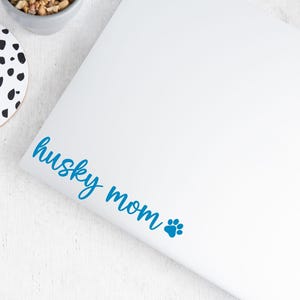 Blue Husky Mom decal with a paw print placed on a laptop.
