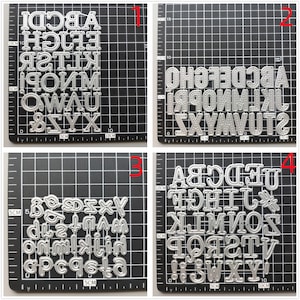 Może przedstawiać: Cztery arkusze metalowych szablon&oacute;w alfabetu do rękodzieła. Każdy arkusz ma inny styl dużych liter, cyfr i znak&oacute;w interpunkcyjnych. Arkusze są ułożone na czarnym tle siatki.