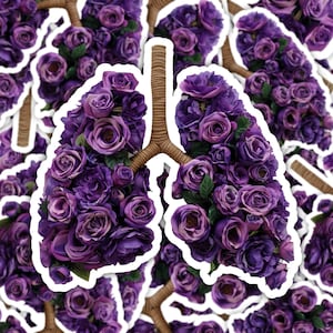 Puede incluir: Un ramo de flores moradas con forma de pulmones. Las flores están dispuestas en forma de corazón y están rodeadas por un borde blanco.