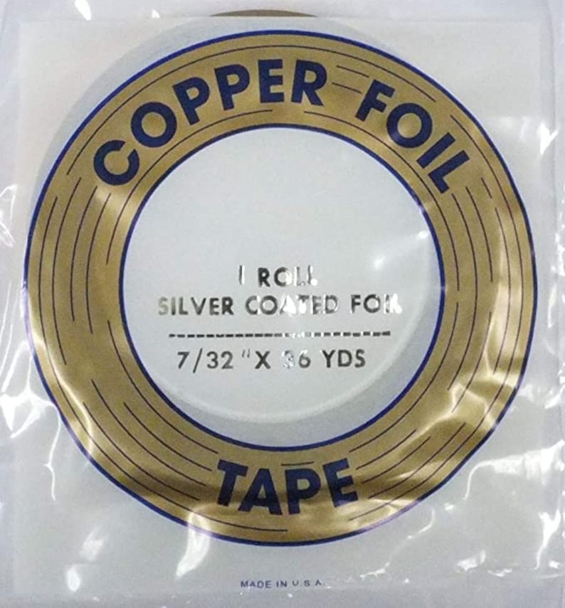 May include: A roll of 7/32 inch by 36 yard copper foil tape, silver coated. The tape is packaged in a clear plastic bag with a gold and blue label that reads "COPPER FOIL TAPE" and "I ROLL SILVER COATED FOR 7/32" X 36 YDS". The label also includes the text "MADE IN U.S.A.".