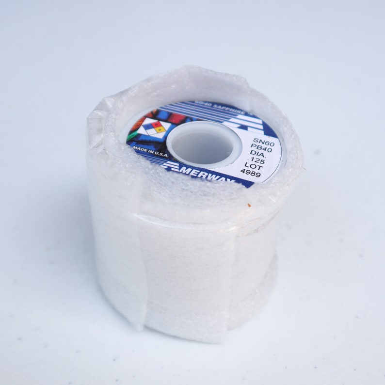 May include: A roll of solder wire with a blue and white label. The label reads "SN60 PB40 DIA. 1.25 LOT 4989" and "MERWAY" in a blue banner. The label also includes a small American flag graphic.