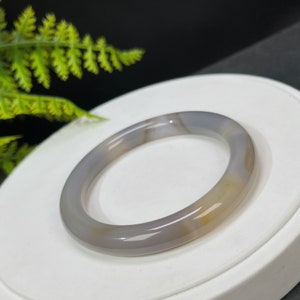 May include: A gray and white agate bangle bracelet with a smooth, polished finish.