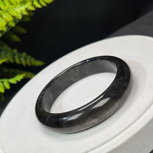 May include: A black jade bangle bracelet with a smooth, polished finish.