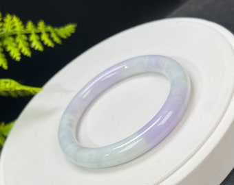 May include: A light green and lavender jade bangle bracelet. The bracelet is smooth and polished.