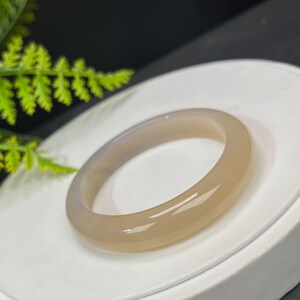 May include: A light brown agate bangle bracelet. The bracelet is smooth and polished.