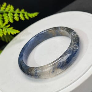 May include: A blue and white agate bangle bracelet with a translucent finish. The bracelet is made of natural stone and has a unique pattern.