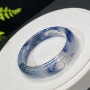 May include: A blue and white agate bangle bracelet. The bangle is made of polished agate and has a swirling blue pattern.