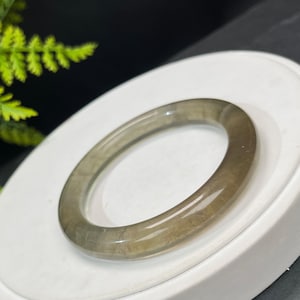 May include: A light green jade bangle bracelet with a smooth, polished finish.