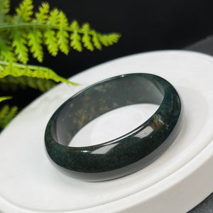 May include: A dark green agate ring with a smooth, polished finish. The ring is made of natural stone and has a unique, organic pattern.