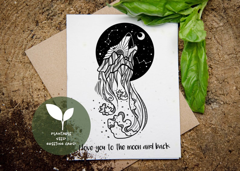 Pu&ograve; includere: Biglietto di auguri con semi piantabili in bianco e nero con un disegno di lupo che ulula. Il lupo &egrave; sagomato contro un cielo stellato con la scritta "I love you to the moon and back". Il biglietto &egrave; su una superficie di legno.