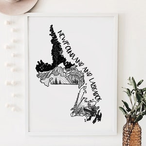 May include: Framed black and white art print depicting a map of Newfoundland and Labrador. The print includes the text "NEWFOUNDLAND AND LABRADOR" in a handwritten style, with illustrations of mountains, trees, and stars.