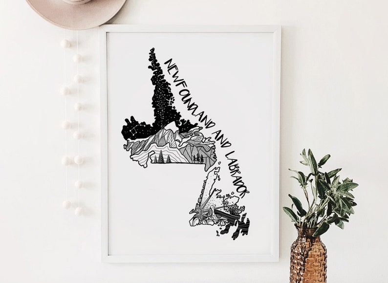 May include: Framed black and white art print depicting a map of Newfoundland and Labrador. The print includes the text "NEWFOUNDLAND AND LABRADOR" in a handwritten style, with illustrations of mountains, trees, and stars.