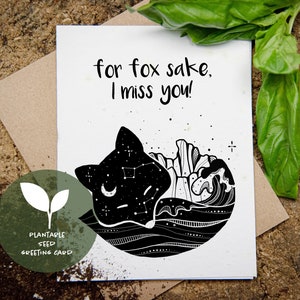 Può includere: Biglietto di auguri bianco con la scritta "for fox sake, I miss you!" e un'illustrazione nera di una volpe con un disegno di cielo stellato. Il biglietto è un biglietto di auguri con semi piantabili.