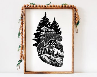 May include: Black and white illustration of a heart with a forest, mountains, and a whale inside. The heart is surrounded by trees and stars.