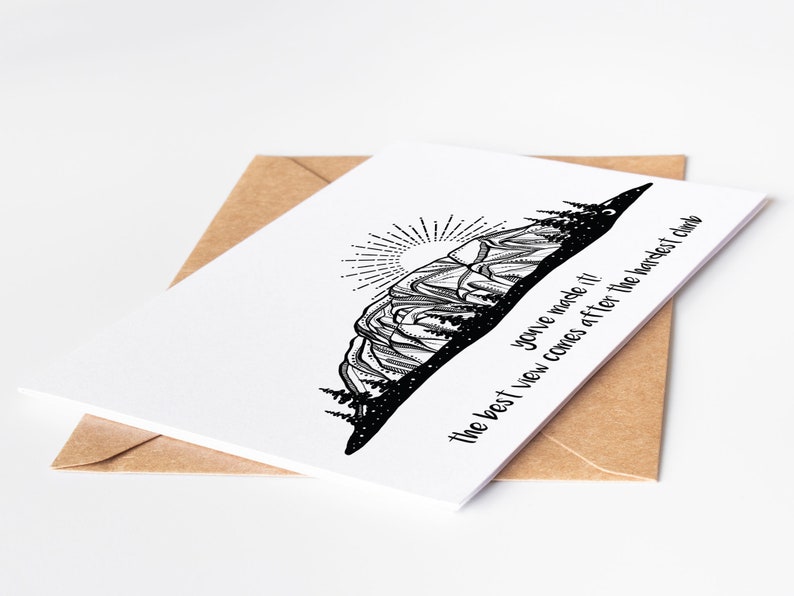 May include: A white greeting card with a black mountain illustration and the text "You've made it! The best view comes after the hardest climb." The card is inside a brown envelope.