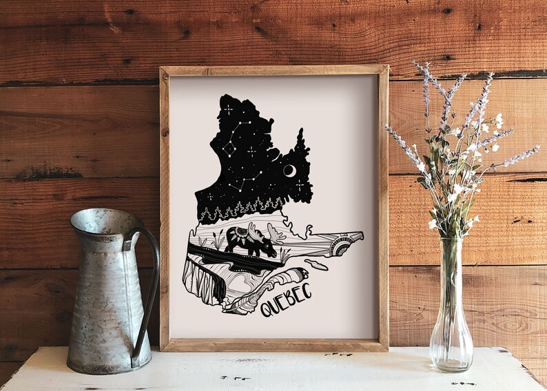 May include: A framed art print featuring a black and white illustration of the Quebec province. The artwork includes a starry night sky, a moose, and the word "QUEBEC". The print is displayed on a white surface with a metal pitcher and a vase of flowers.