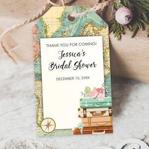 May include: A gift tag with a vintage map design, featuring the text "Thank you for coming! Jessica's Bridal Shower" and the date. The tag includes a stack of suitcases and a compass illustration. The tag is tied to a wrapped gift.