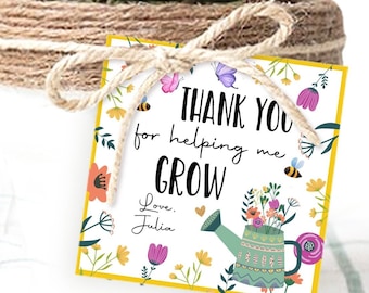 Puede incluir: Una tarjeta blanca con un borde amarillo y un diseño floral. La tarjeta dice "Gracias por ayudarme a crecer. Con cariño, Julia". Hay una regadera con flores en ella.