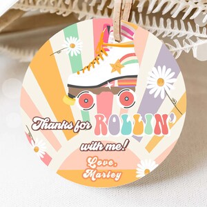 May include: A round, colorful thank you tag with a retro roller skate design. The tag features a white roller skate with rainbow accents and a yellow star. The text on the tag reads "Thanks for rollin' with me! Love, Marley".