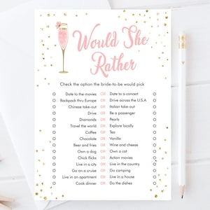 May include: A pink and gold bridal shower game with the text "Would She Rather" and a list of questions for guests to answer. The game features a pink champagne glass with a gold rim and a pink flower.