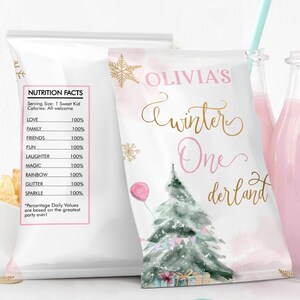 May include: A party favor bag with the text "Olivia's Winter One derland" and a watercolor Christmas tree design. Two bottles of pink liquid with blue straws are visible. The bag has a nutrition facts label.
