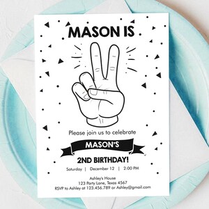Może przedstawiać: Czarno-białe zaproszenie na urodziny z ręką wykonującą znak pokoju. Tekst brzmi "MASON IS" i "MASON'S 2ND BIRTHDAY!" z datą i godziną imprezy.