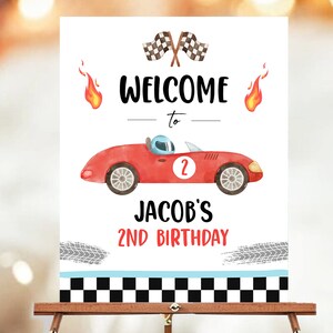 May include: Welcome to Jacob's 2nd Birthday party sign with a red race car, checkered flags, and flames.