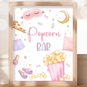 May include: A printable sign for a popcorn bar with a pink and purple sleep theme. The sign features a pink sleep mask, a purple pair of pajamas, a pink pillow, a pink and white striped popcorn bucket, and the text "Popcorn Bar".