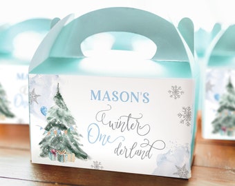 May include: Light blue gable box with a handle, featuring a watercolor illustration of a Christmas tree, snowflakes, and the text "MASON'S Winter One derland." The box is designed for a winter-themed celebration.