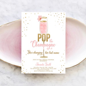 Könnte beinhalten: Rosafarbene und goldene Einladung zur Bridal Shower mit einer Champagnerflötengrafik und dem Text "Pop the Champagne She's changing her last name". Die Einladung enthält den Namen der Braut, Datum, Uhrzeit, Ort und RSVP-Informationen.